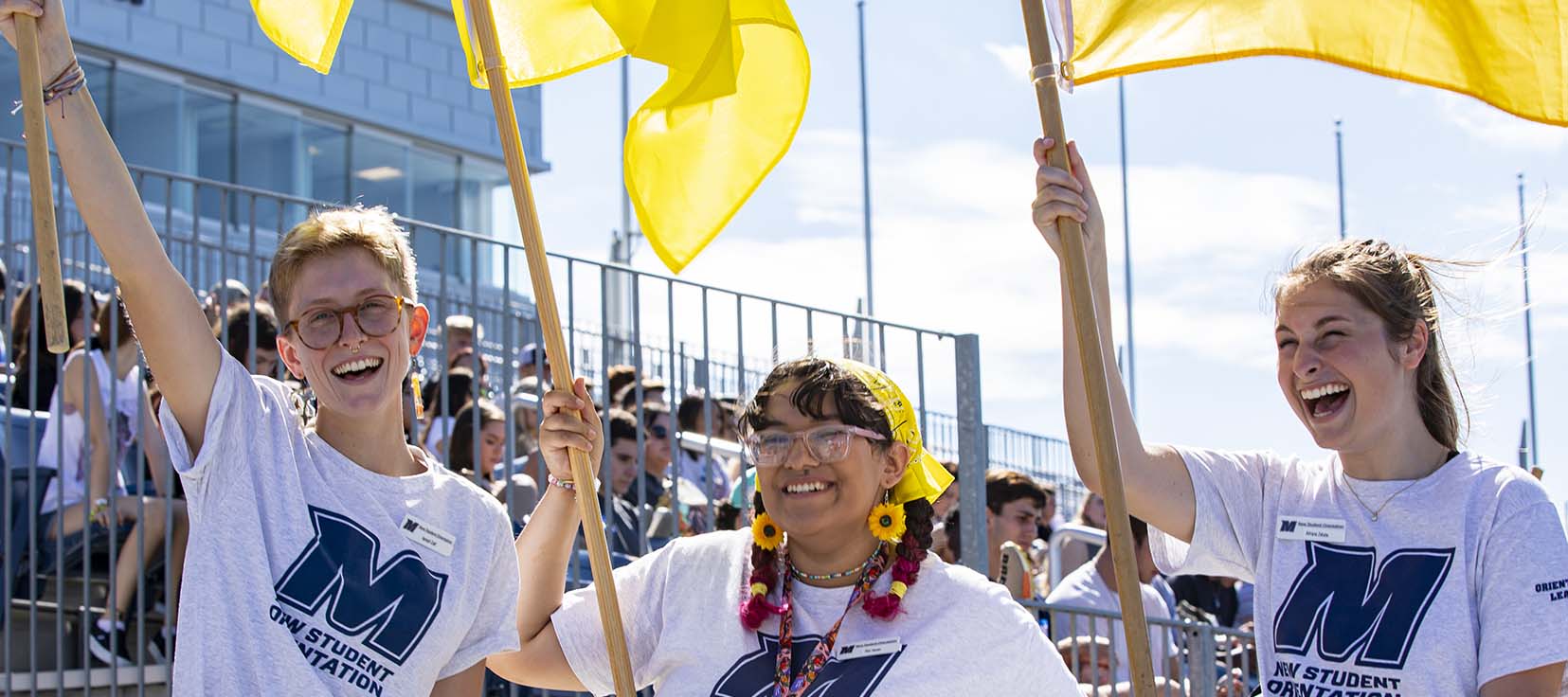 Three students with yellow flags as part of the new student welcome