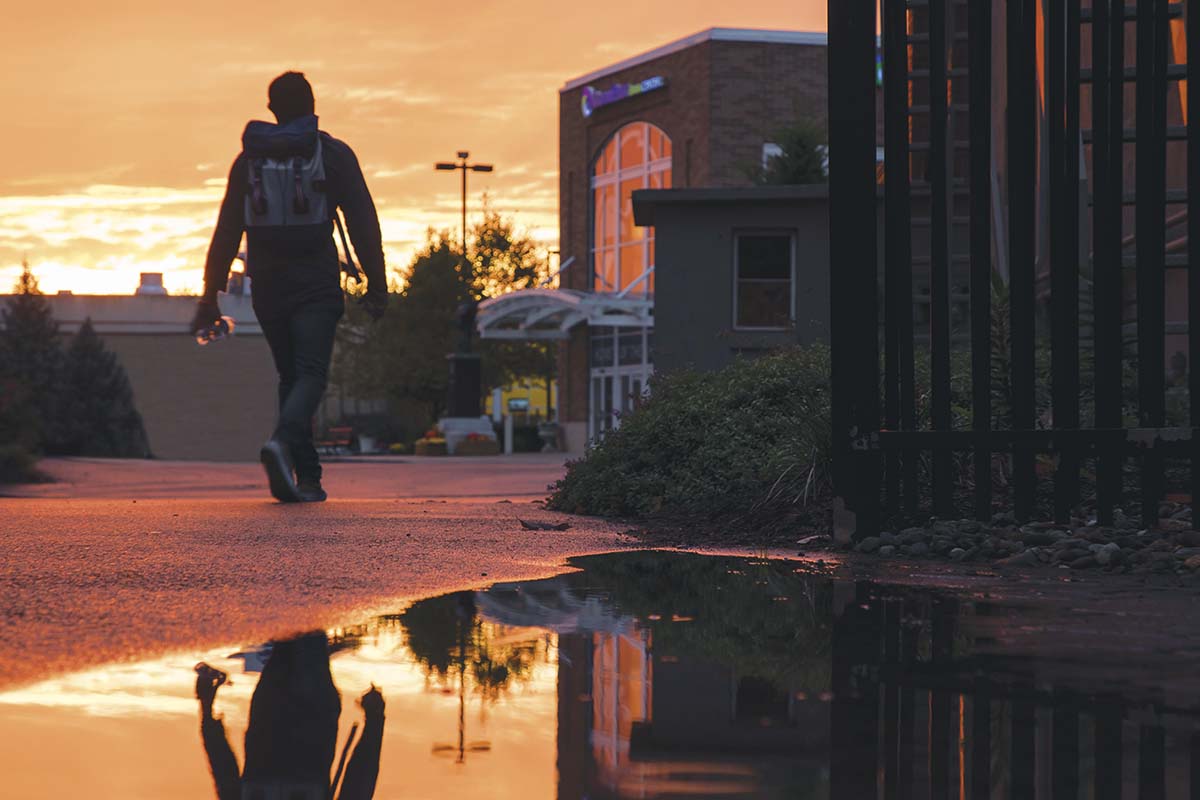 Student walking on campus at sunset
