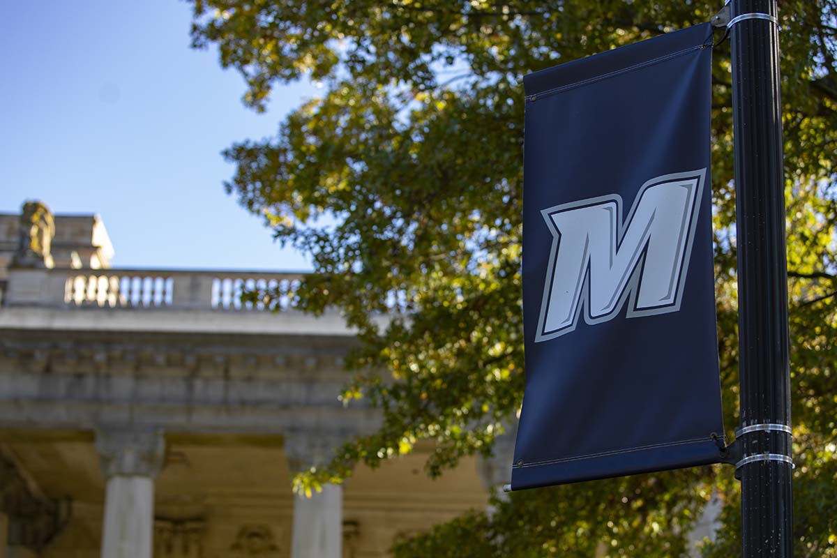 Monmouth University flag on pole with school in background