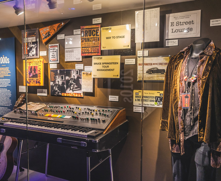 keyboard, outfit, and a variation of posters and signs in a Bruce Springsteen exhibit