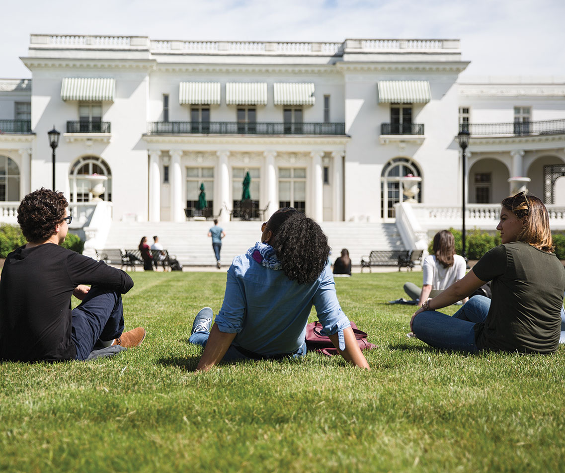 A group of Monmouth University students lay back on the grass outside as they chat amongst each other