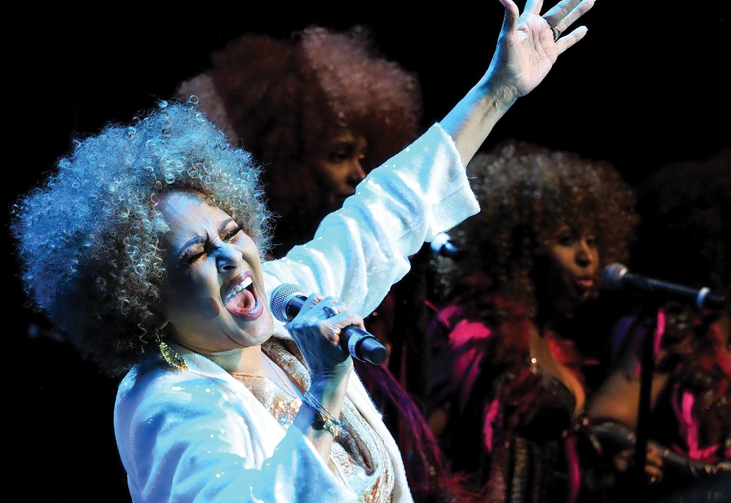 Woman performing on stage as she sings into the microphone plus other background singers behind her inside at The American Music Honors show event presented by The Bruce Springsteen Archives and Center for American Music