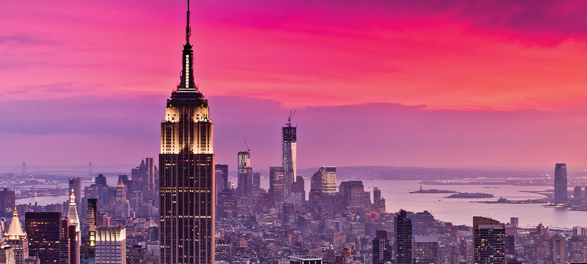 New York cityscape with a focus on the Empire State Building standing majestically against a vibrant pink and magenta sunset, showcasing the structure's iconic Art Deco architecture against the skyline