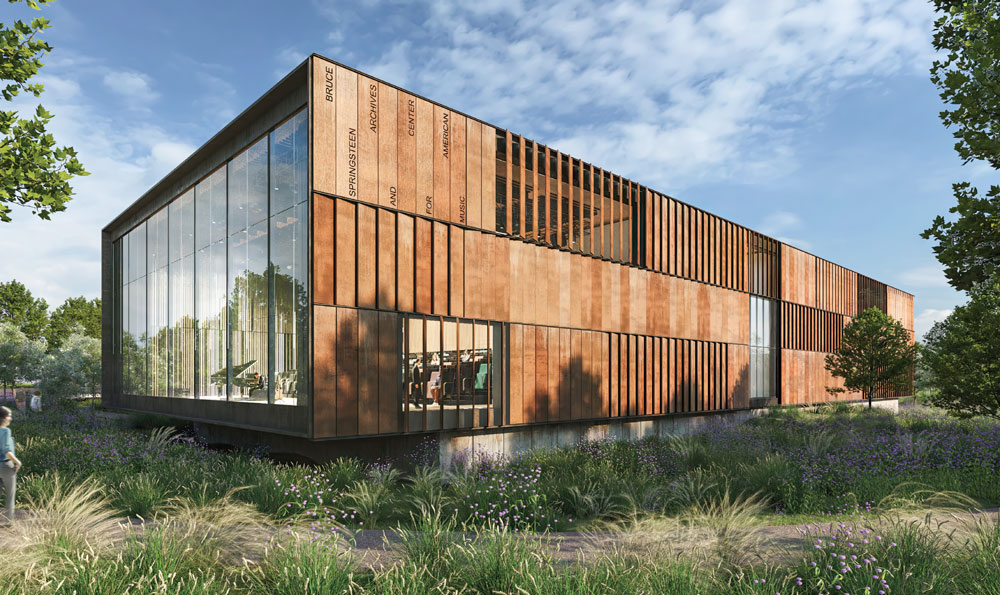 Modern building with glass windows and rust-colored panels, surrounded by greenery.