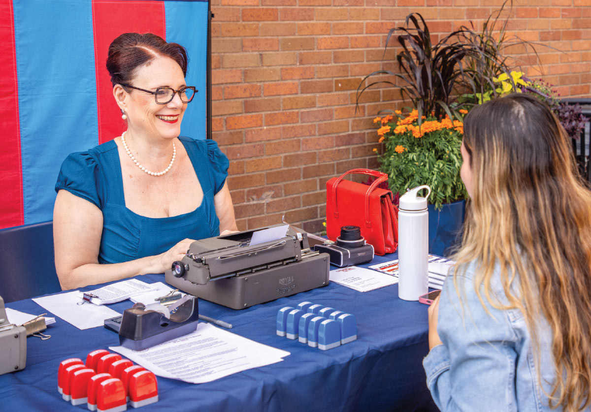 Sheryl Oring smiling while sitting across from another person at an event table