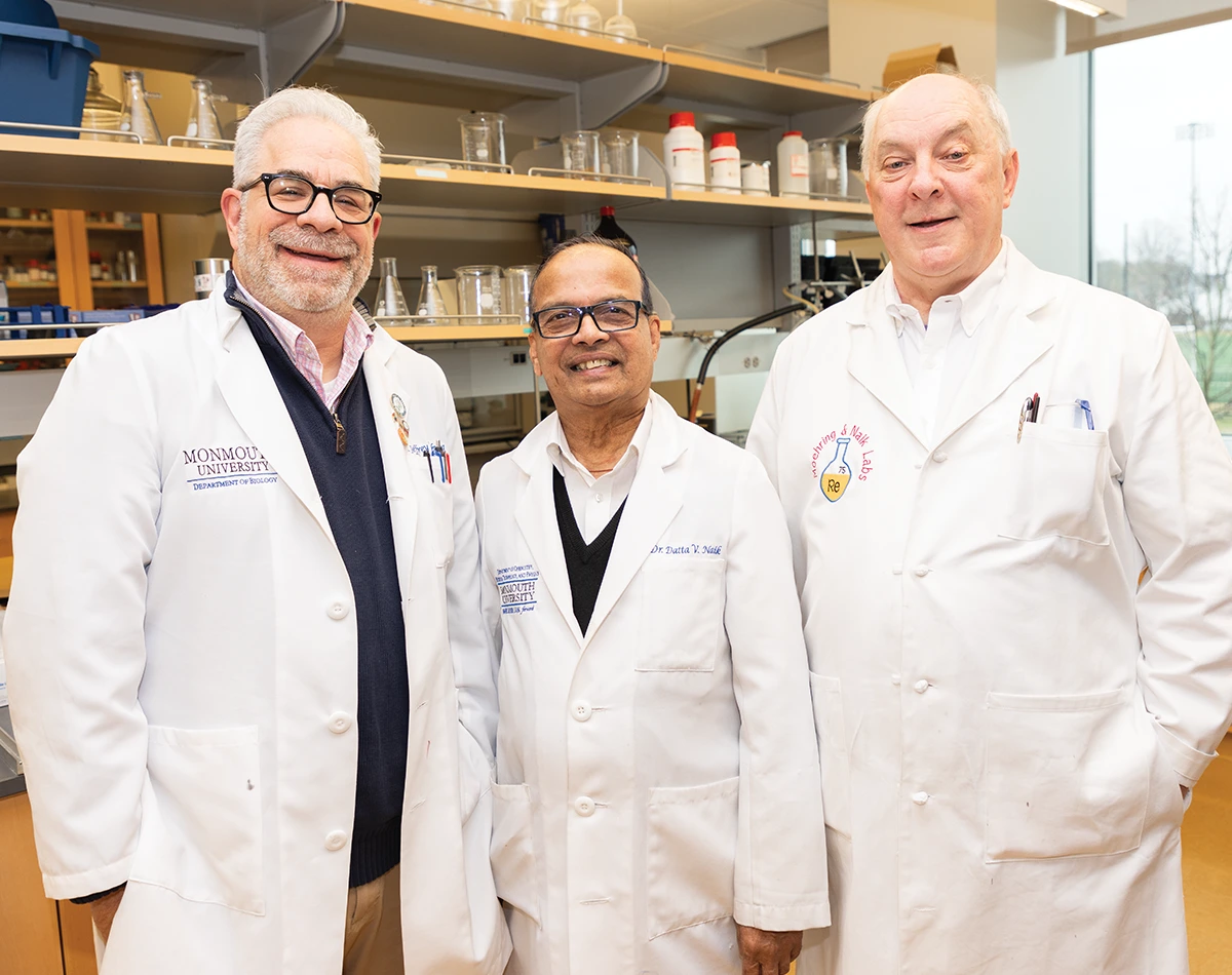 Jeffrey Weisburg, Datta Naik, and Greg Moehring wearing white lab coats and posing together in a lab