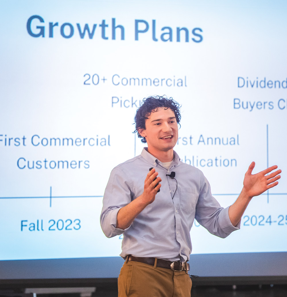 candid shot of a mic'd man giving a presentation in front of a large projector