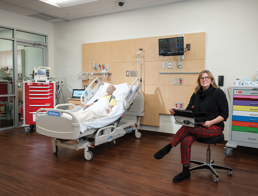 office coordinator Billie McNally pictured sitting in patient room in the state-of-the-art Linda Grunin Simulation Lab health care training facility